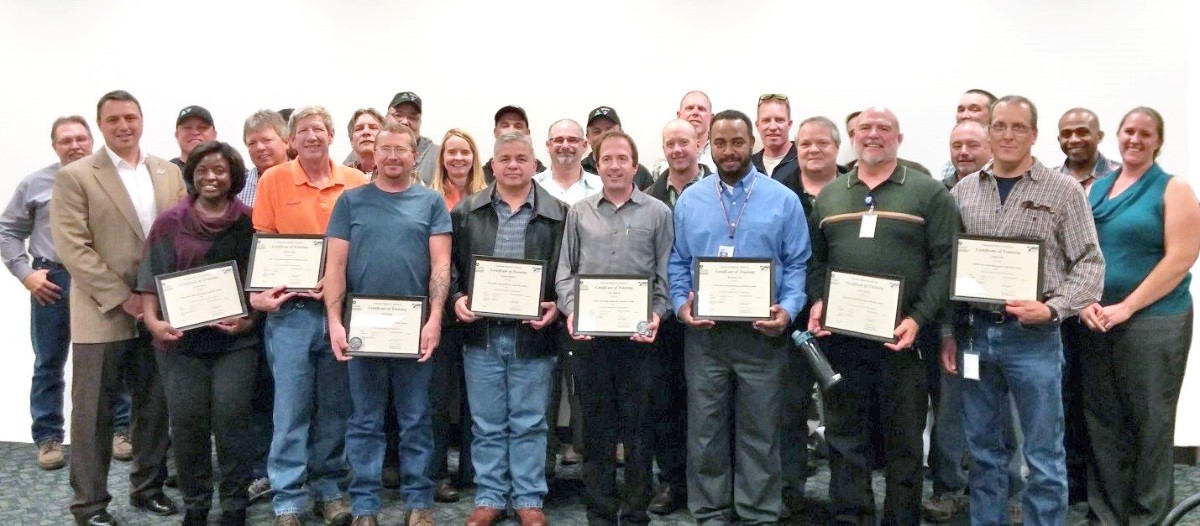 Group photo of the NHI Maintenance Leadership Academy (MLA) course graduates holding their certificates of completion.